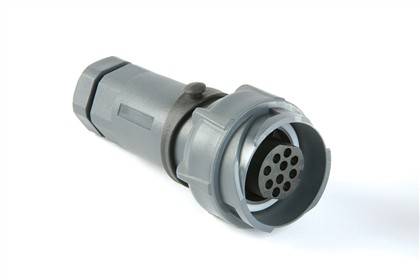Ein zylindrischer, grauer elektrischer Stecker mit mehreren kreisförmigen Kontaktstiften, der zum Verbinden kompatibler Geräte verwendet wird.