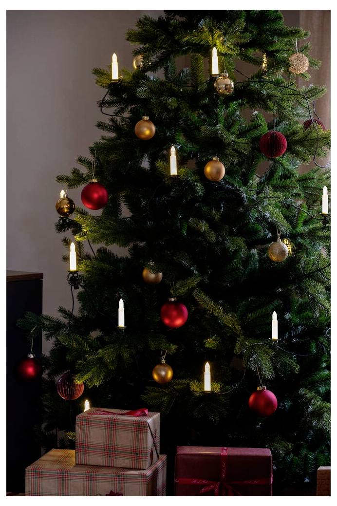 Ein geschmückter Weihnachtsbaum mit Kerzen und roten und goldenen Weihnachtskugeln, umgeben von verpackten Geschenken in der Nähe.