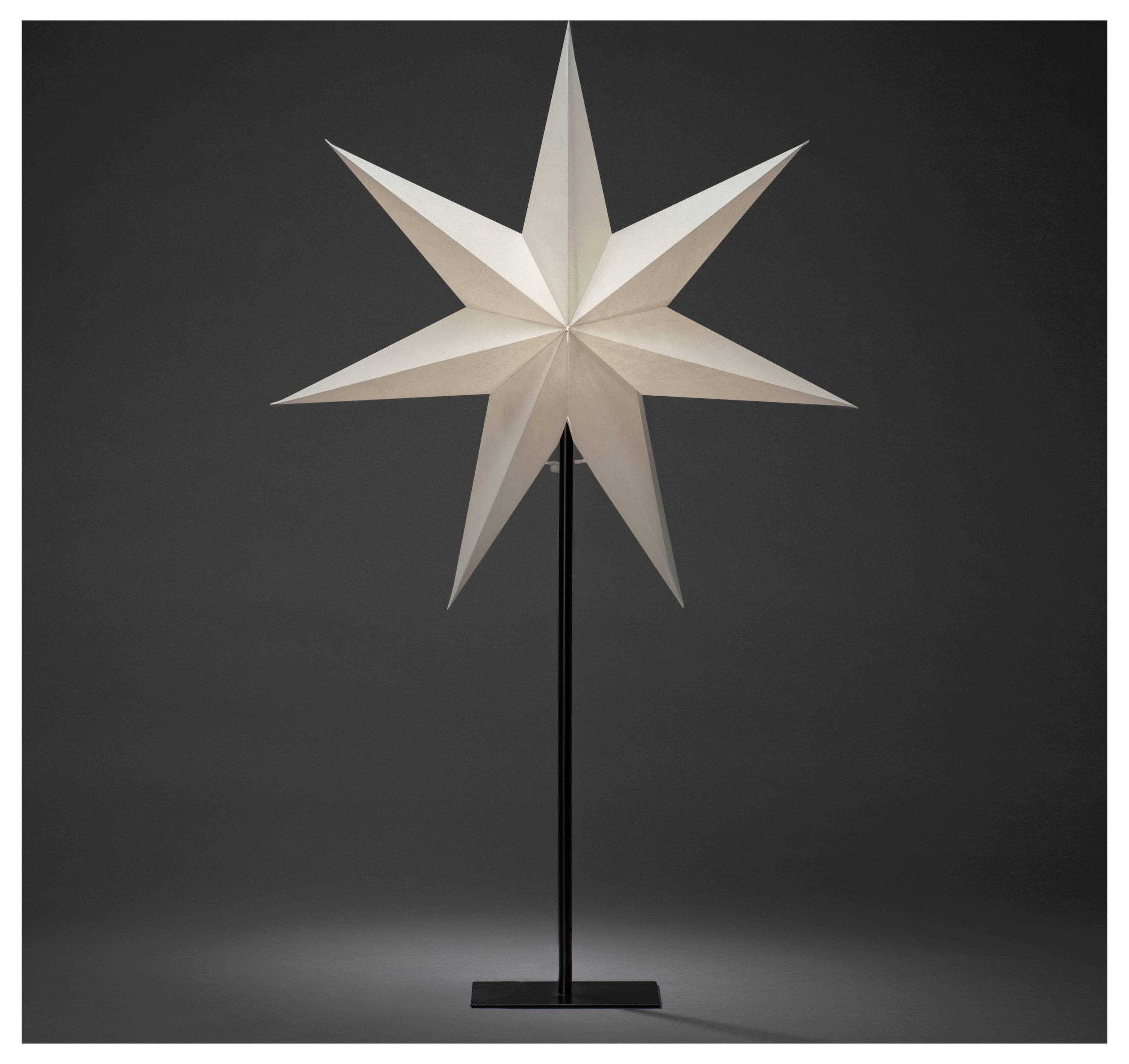 Ein weißer, achtzackiger Papierstern steht auf einem schwarzen Metallständer vor einem dunklen Hintergrund.