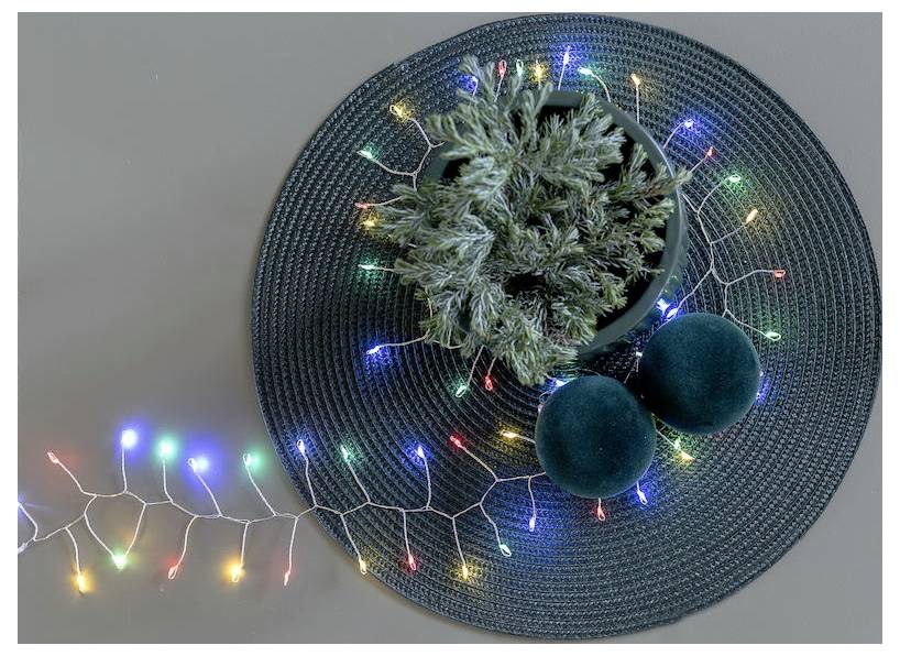 Rundes Matte mit einer gefrosteten Kiefer und zwei grünen Ornamenten, umgeben von bunten Lichterketten.