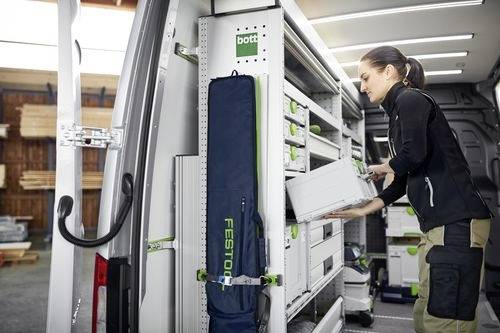 Eine Person, die Werkzeuge in einem gut ausgestatteten Transporter organisiert und einen Koffer auf Regalen mit der Aufschrift „bott
