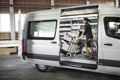 Eine Person lädt Ausrüstung in einen organisierten Lieferwagen mit Regalen innerhalb eines Lagerhauses und demonstriert damit effizientes Platzmanagement.