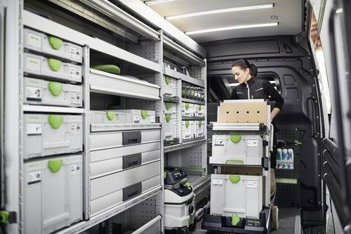 Ein Techniker in einem gut organisierten Servicefahrzeug ordnet Ausrüstung und Werkzeuge in beschrifteten Stauraum an und bereitet sich auf eine Arbeitsaufgabe vor.