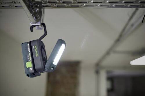 Eine tragbare Arbeitsleuchte hängt von einer Metallschiene in einer Garage und beleuchtet den Raum mit ihrem hellen LED-Streifen.