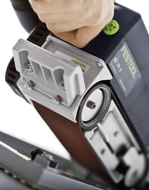 Eine Hand bedient eine Festool BS 75 Bandschleifer und konzentriert sich auf die Kontrolleinstellungen und das Schleifband, wobei die Werkzeugeinstellung in Aktion gezeigt wird.