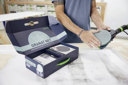 Eine Person, die eine Oberfläche mit einem Schleifwerkzeug schleift, neben einer geöffneten Box mit der Beschriftung 