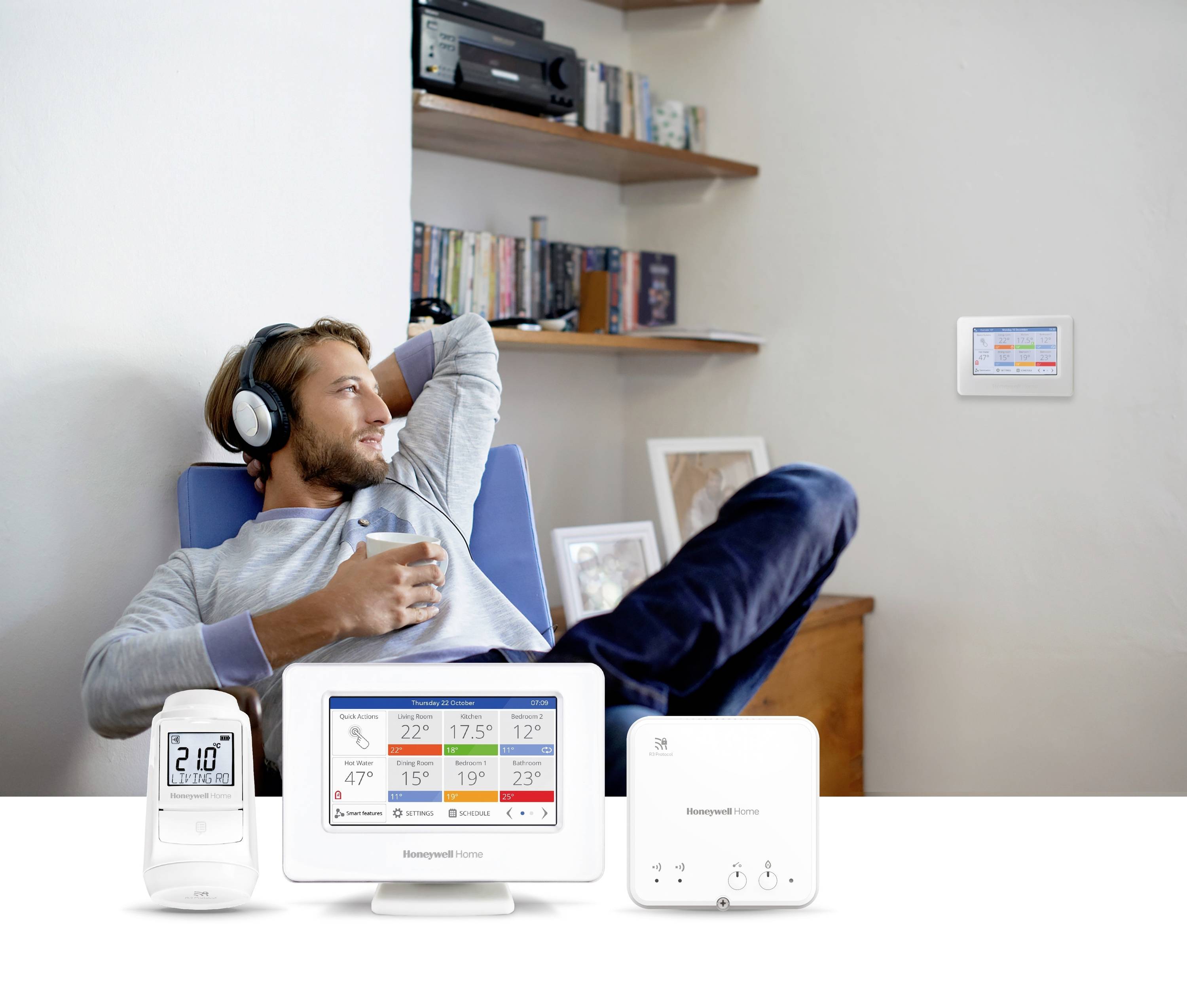 Eine Person mit Kopfhörern entspannt sich auf einem Stuhl und blickt auf einen an der Wand montierten Smart-Thermostat, der Temperatureinstellungen anzeigt.