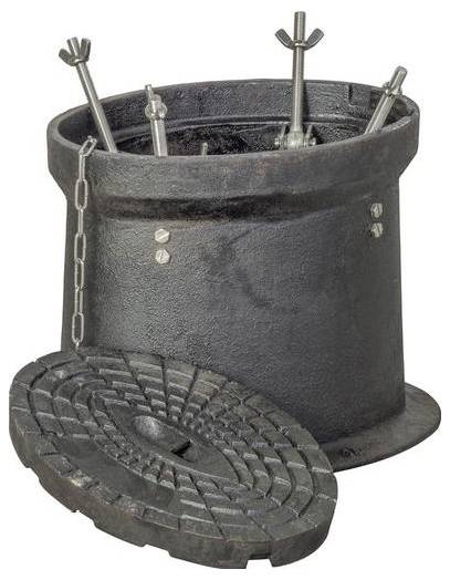 Dunkler zylindrischer Behälter enthält metallische Stäbe mit Flügelmuttern; ein abgenommener strukturierter kreisförmiger Deckel ruht an der Basis und ist durch eine Kette verbunden.