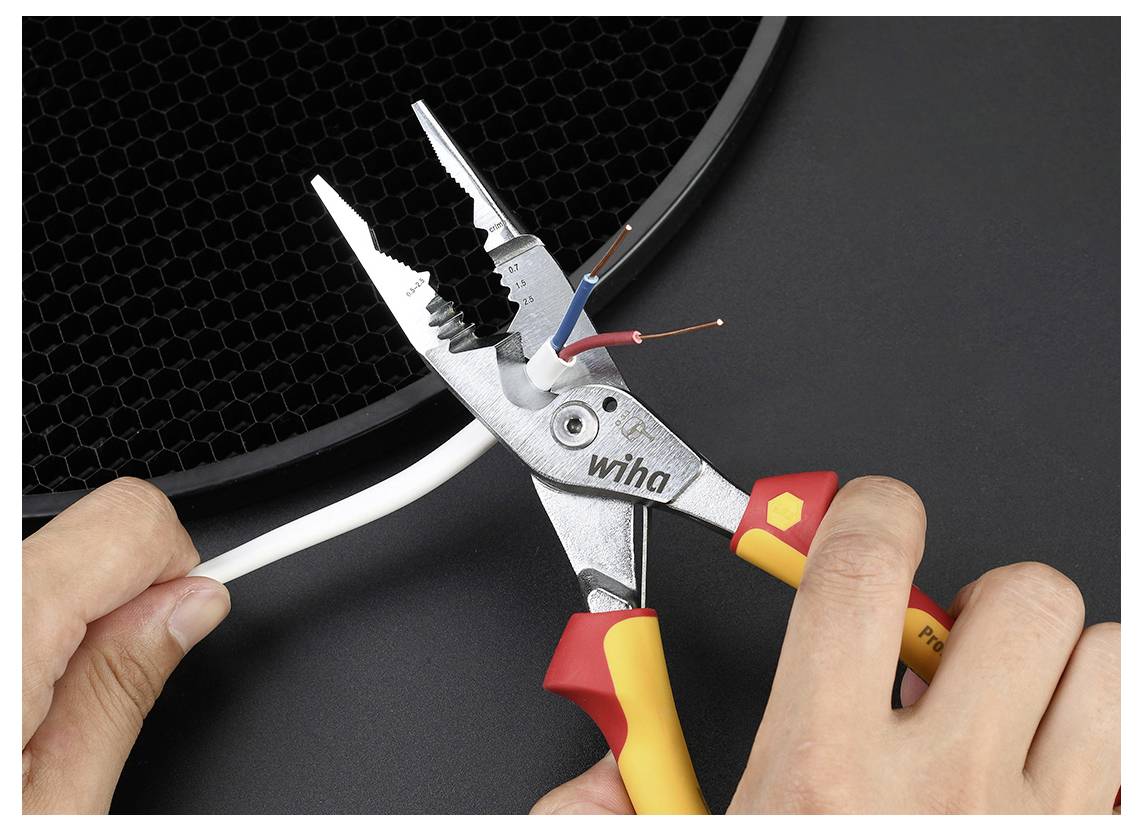 Hände, die ein Abisolierwerkzeug verwenden, um die Isolierung von einem weißen Kabel zu entfernen und dabei die farbigen Drähte im Inneren freizulegen.