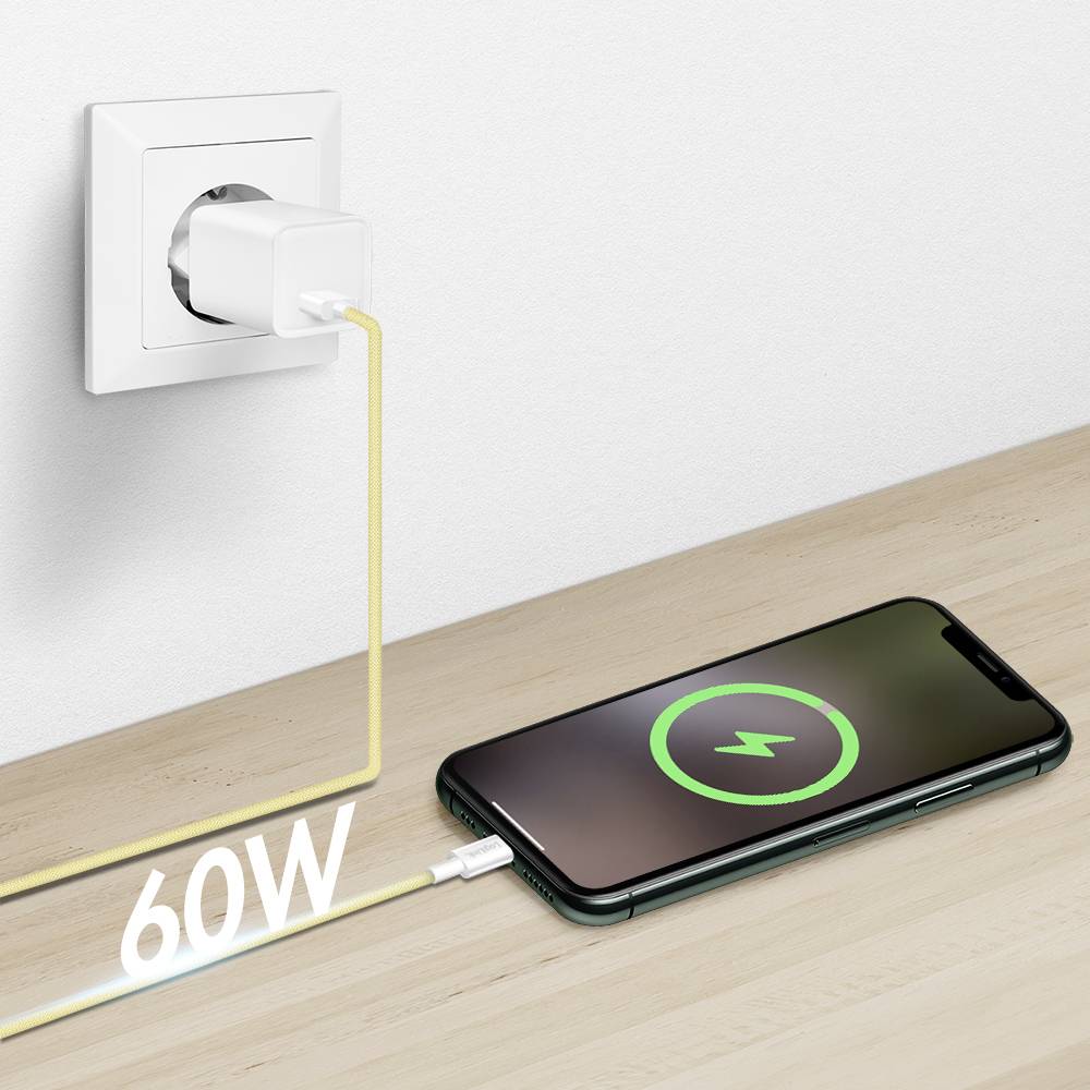 Ein Smartphone liegt auf einem Tisch und ist über ein Kabel mit einer Steckdose verbunden und zeigt ein Ladessymbol. 