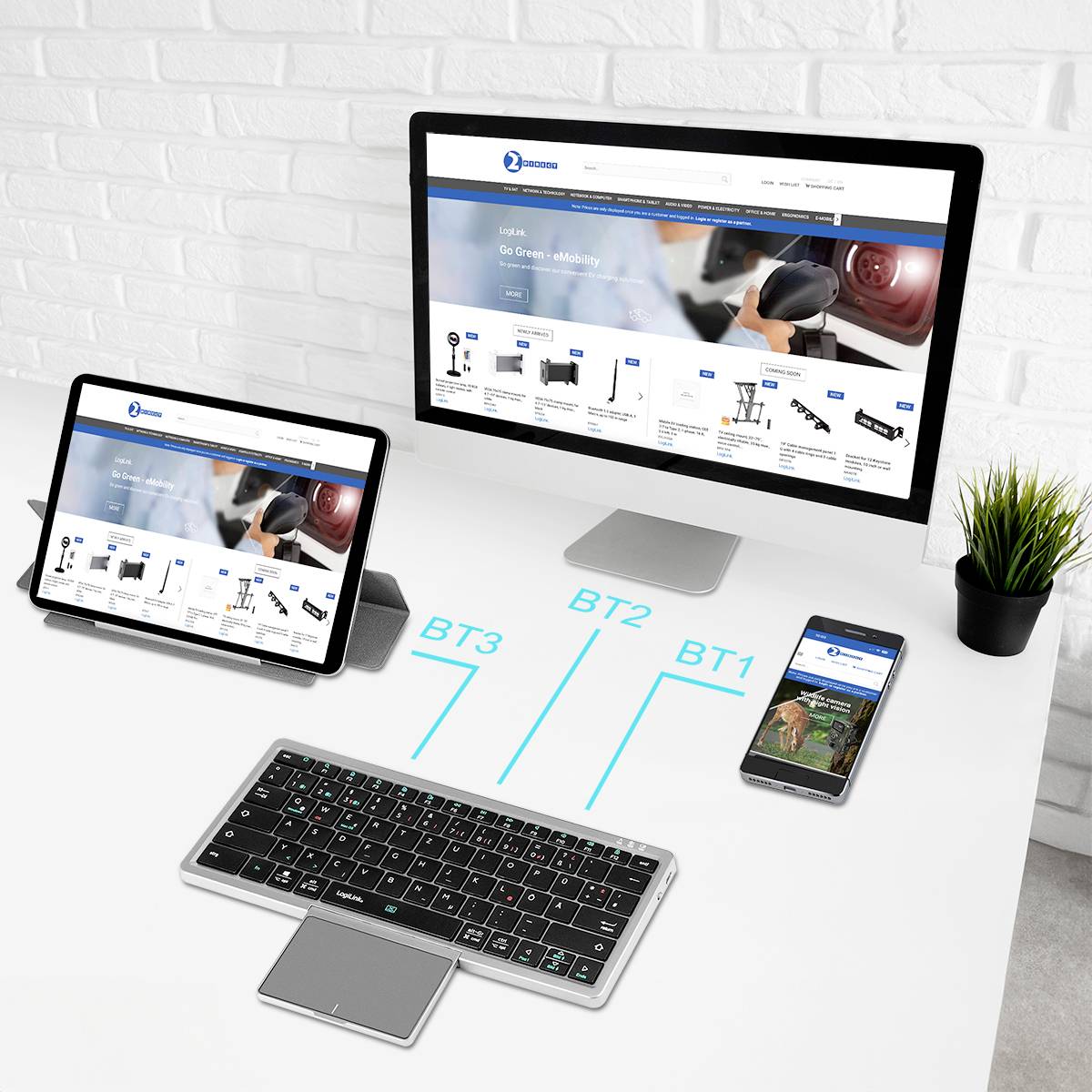 Ein Computermonitor, ein Tablet und ein Smartphone, die dieselbe Website anzeigen, neben einer drahtlosen Tastatur. Das Setup deutet auf Multitasking oder Gerätevernetzung in einem Büroumfeld hin.