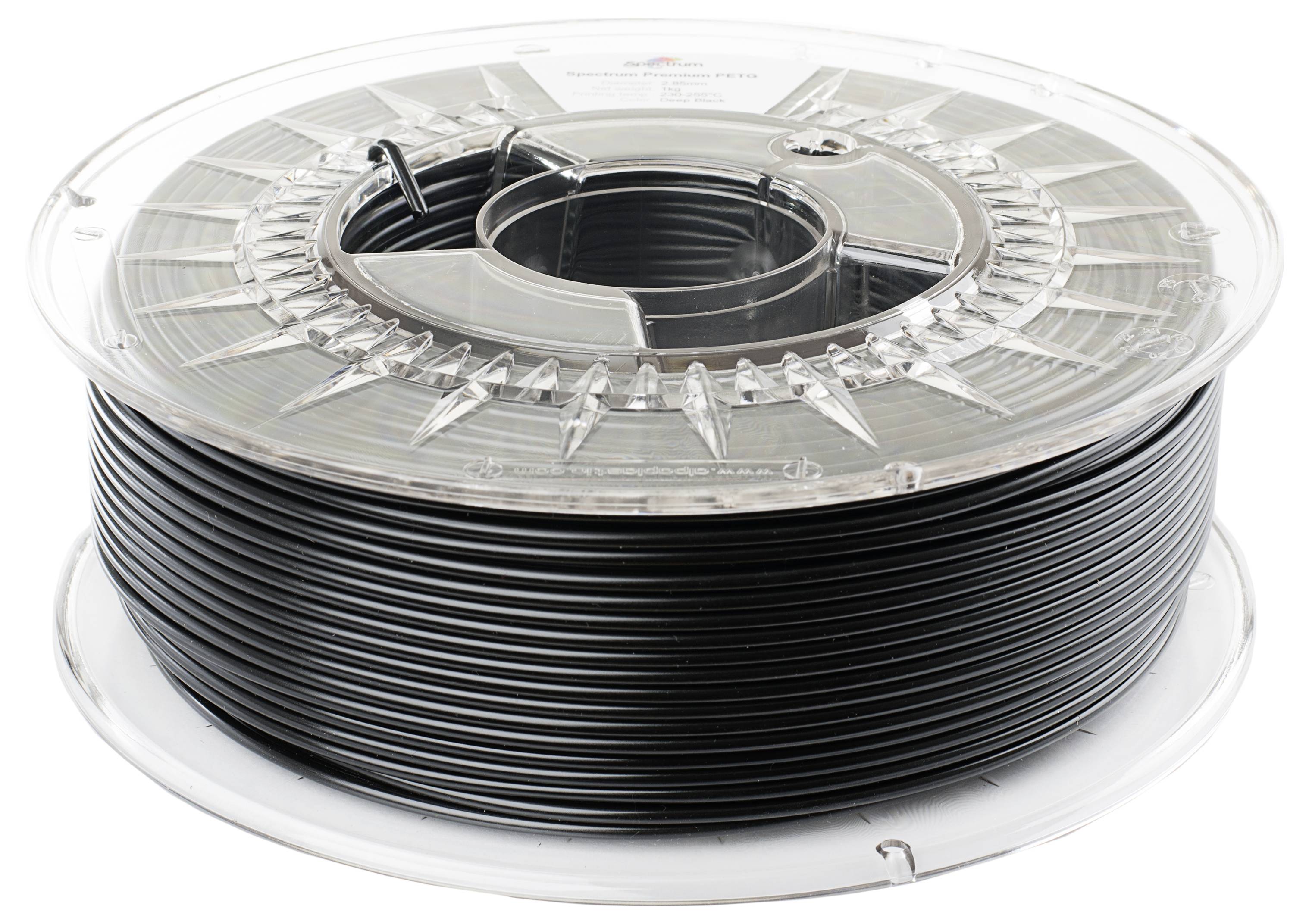 Eine Spule schwarzen 3D-Druckerfilaments mit transparenter Kunststoffummantelung, die auf einer weißen Oberfläche ruht.