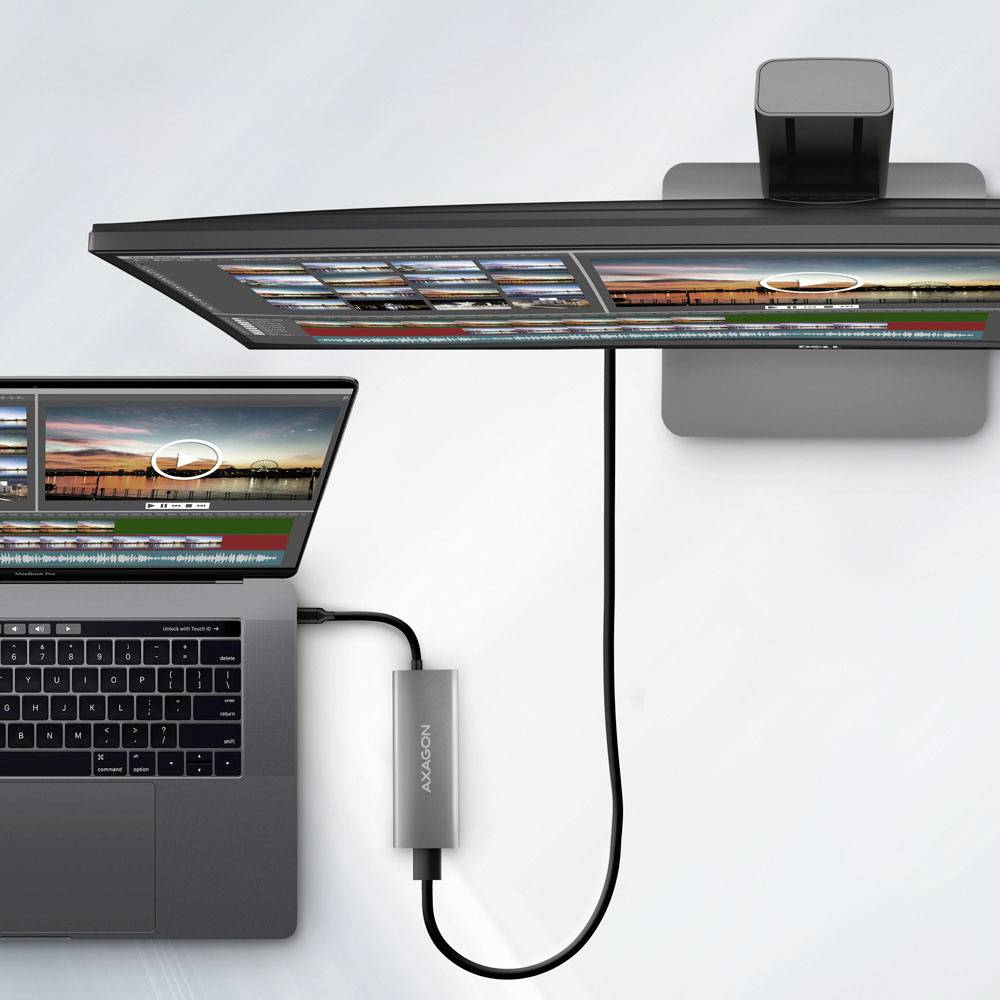 Ein Laptop, der an einen gebogenen Monitor angeschlossen ist und identische Bildbearbeitungssoftware-Bildschirme zeigt, hebt ein produktives Dual-Screen-Setup hervor.