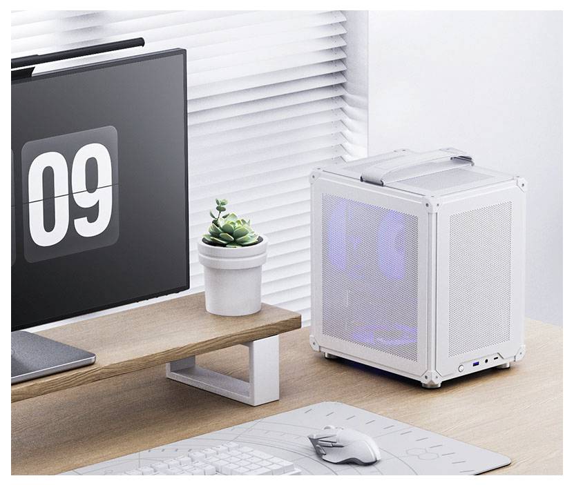 Ein moderner, kompakter weißer Computertower mit sichtbaren Lüftern steht auf einem Schreibtisch neben einem Monitor, der '09' anzeigt, und einer kleinen Topfpflanze.