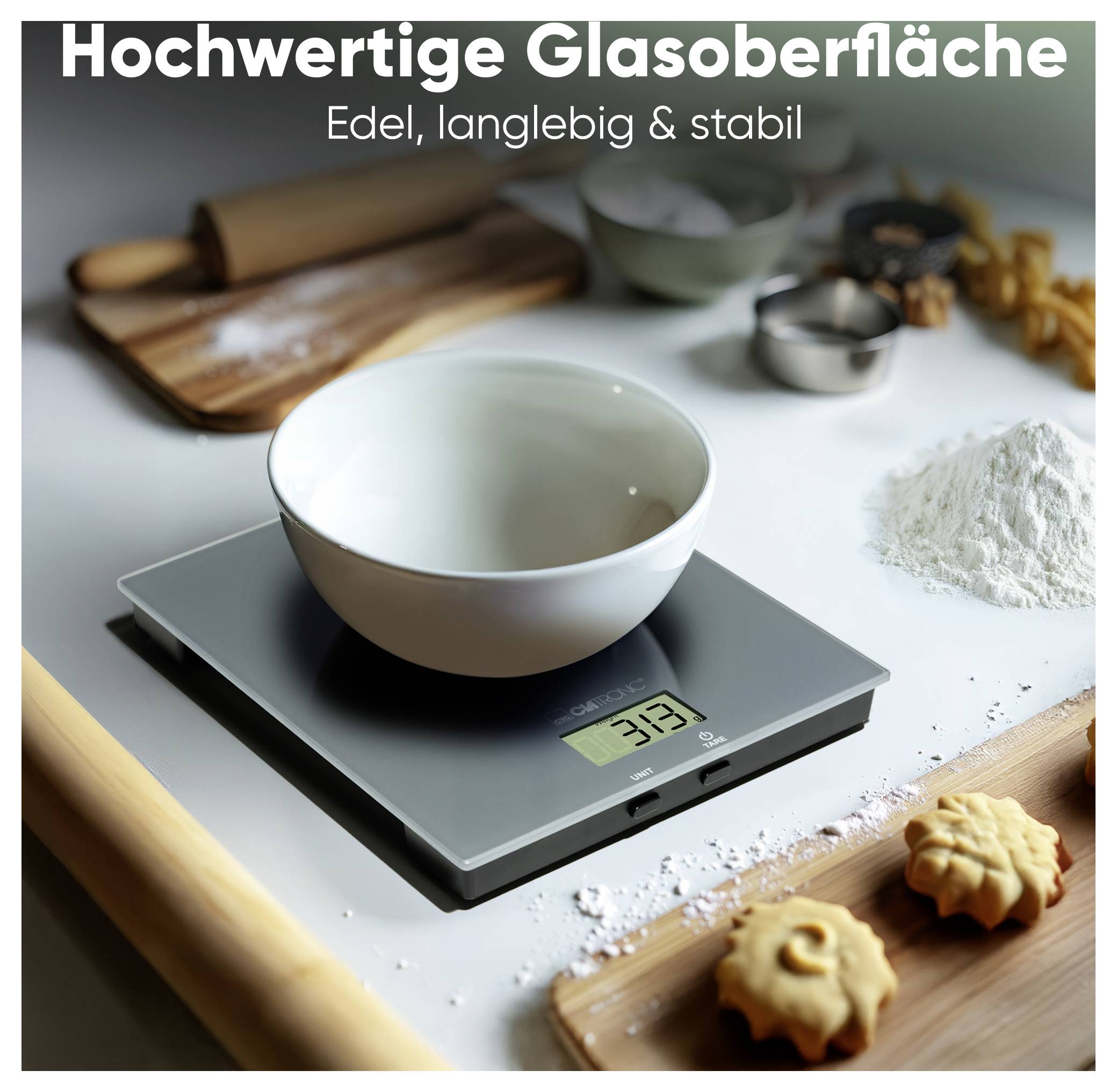 Eine digitale Küchenwaage mit Glasoberfläche zeigt '231' Gramm an, während eine Rührschüssel darauf steht. In der Nähe befinden sich Backzutaten und Küchenutensilien.