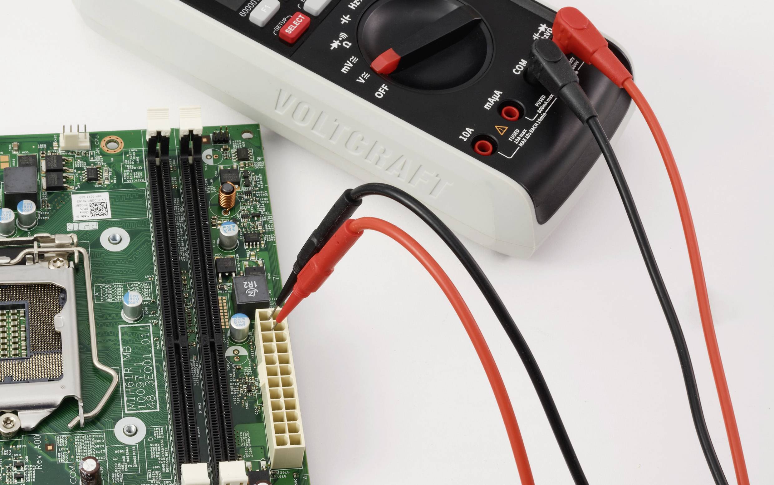 Ein Multimeter, das an ein Computermotherboard angeschlossen ist und elektrische Parameter misst.