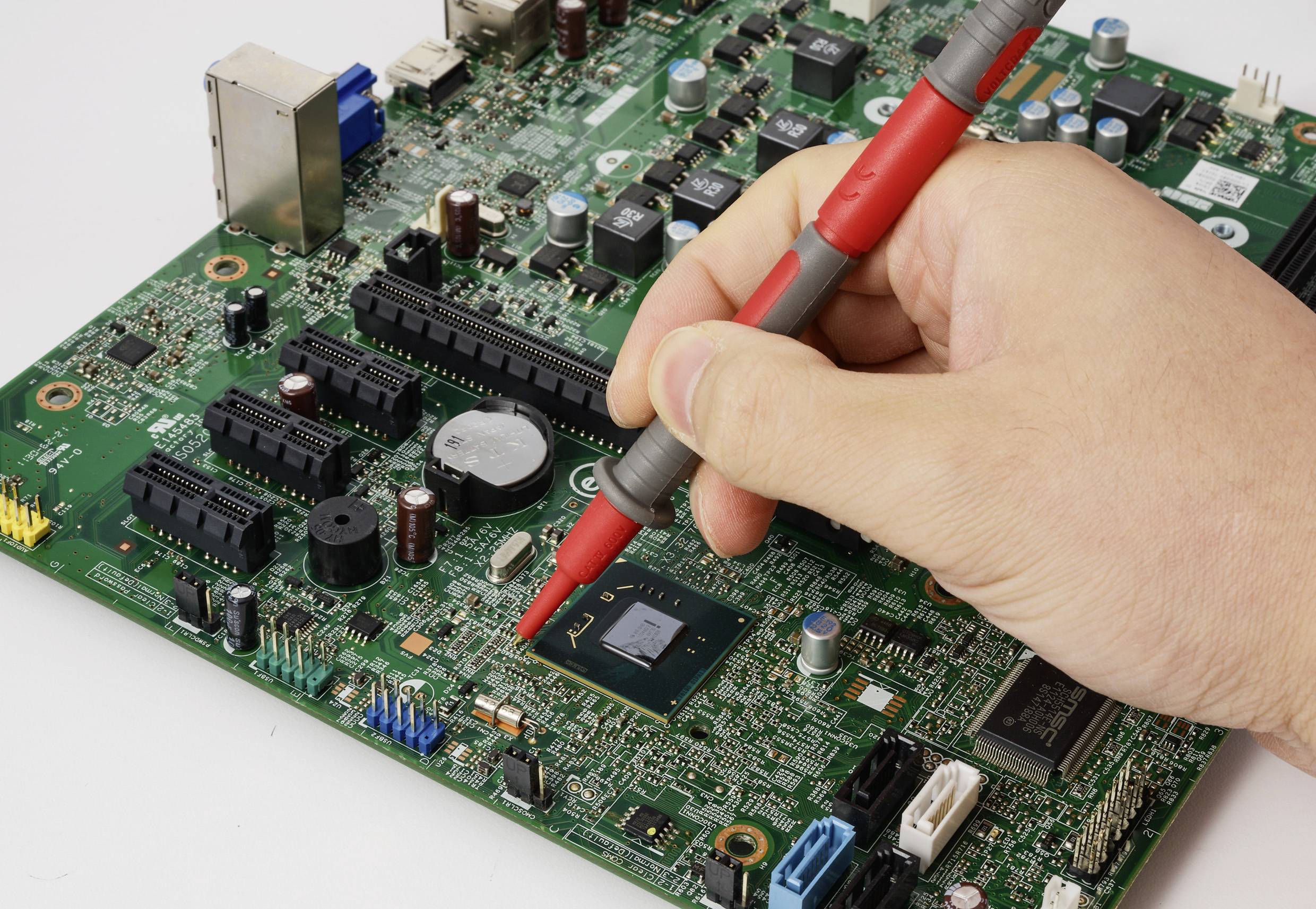 Eine Hand verwendet eine rote Sonde auf einem Computermotheeboard und testet elektronische Komponenten.