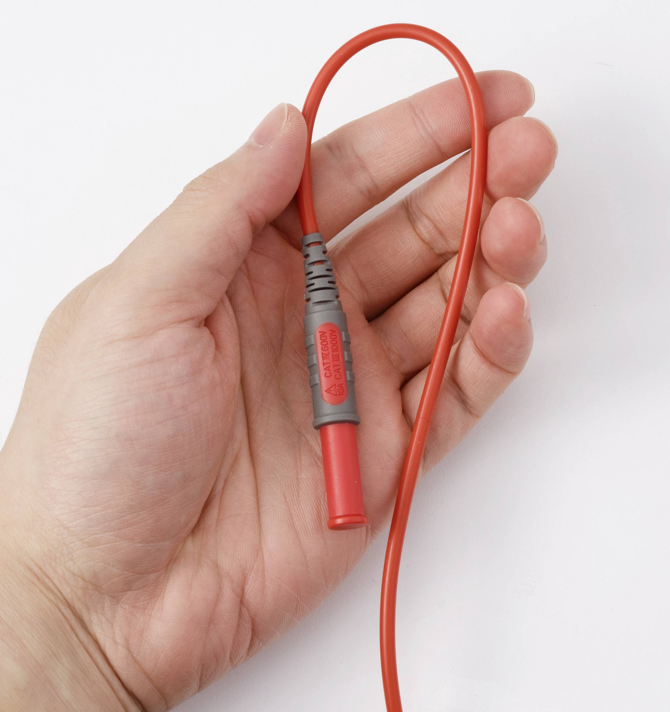 Eine Hand, die eine rote elektrische Messsonde mit einem flexiblen Kabel hält, die zum Testen elektrischer Schaltkreise verwendet wird.