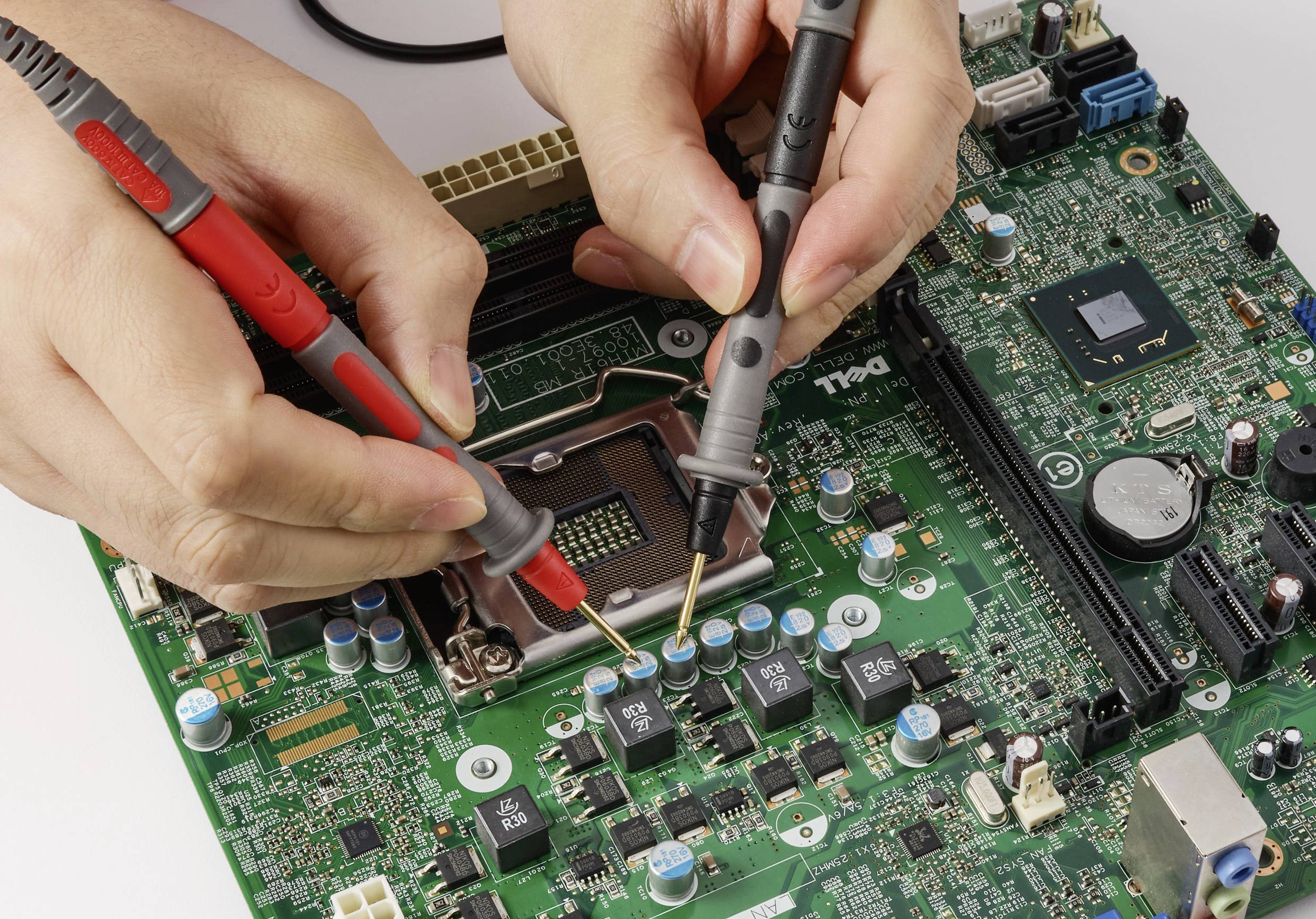 Hände, die Messsonden verwenden, um eine elektronische Leiterplatte mit verschiedenen Komponenten zu testen und zu untersuchen und dabei elektronische Arbeiten veranschaulichen.