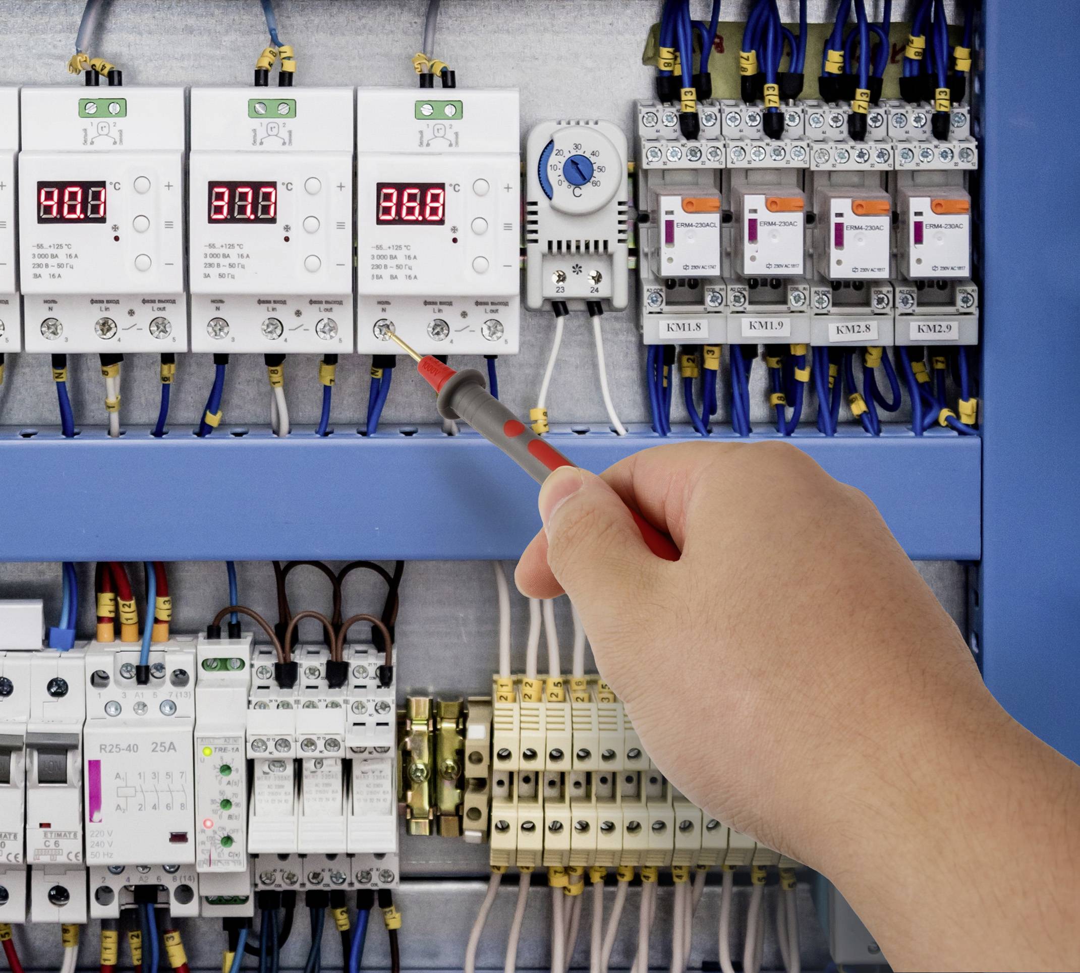 Ein Elektriker verwendet einen Schraubendreher, um Einstellungen an einer Elektrotafel mit digitalen Messgeräten, die Spannungen und Schalter anzeigen, vorzunehmen.