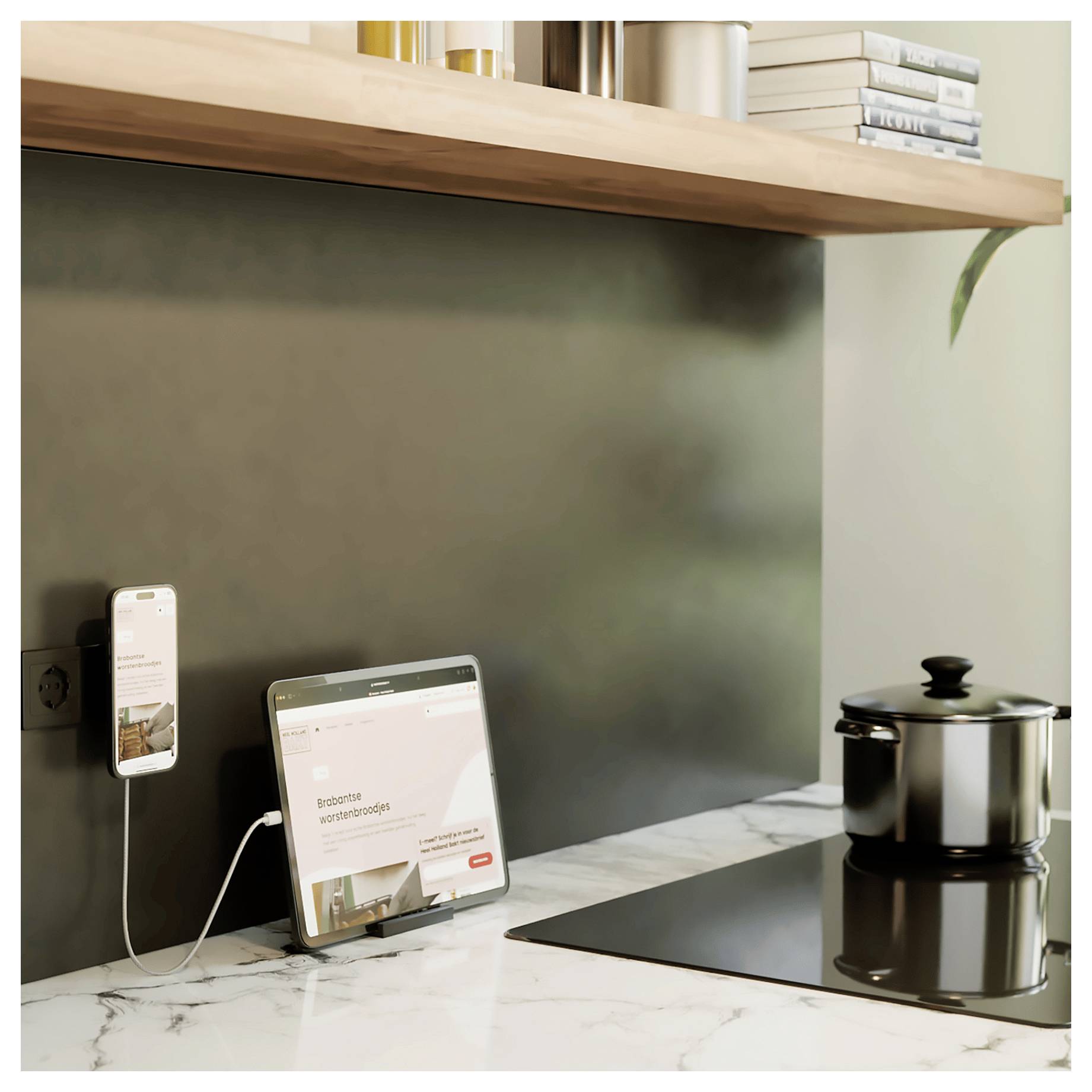 Eine Marmorarbeitsfläche mit einem Tablet, das eine Inneneinrichtungswebsite anzeigt, ein ladendes Telefon und eine Herdplatte mit einem Topf daneben.