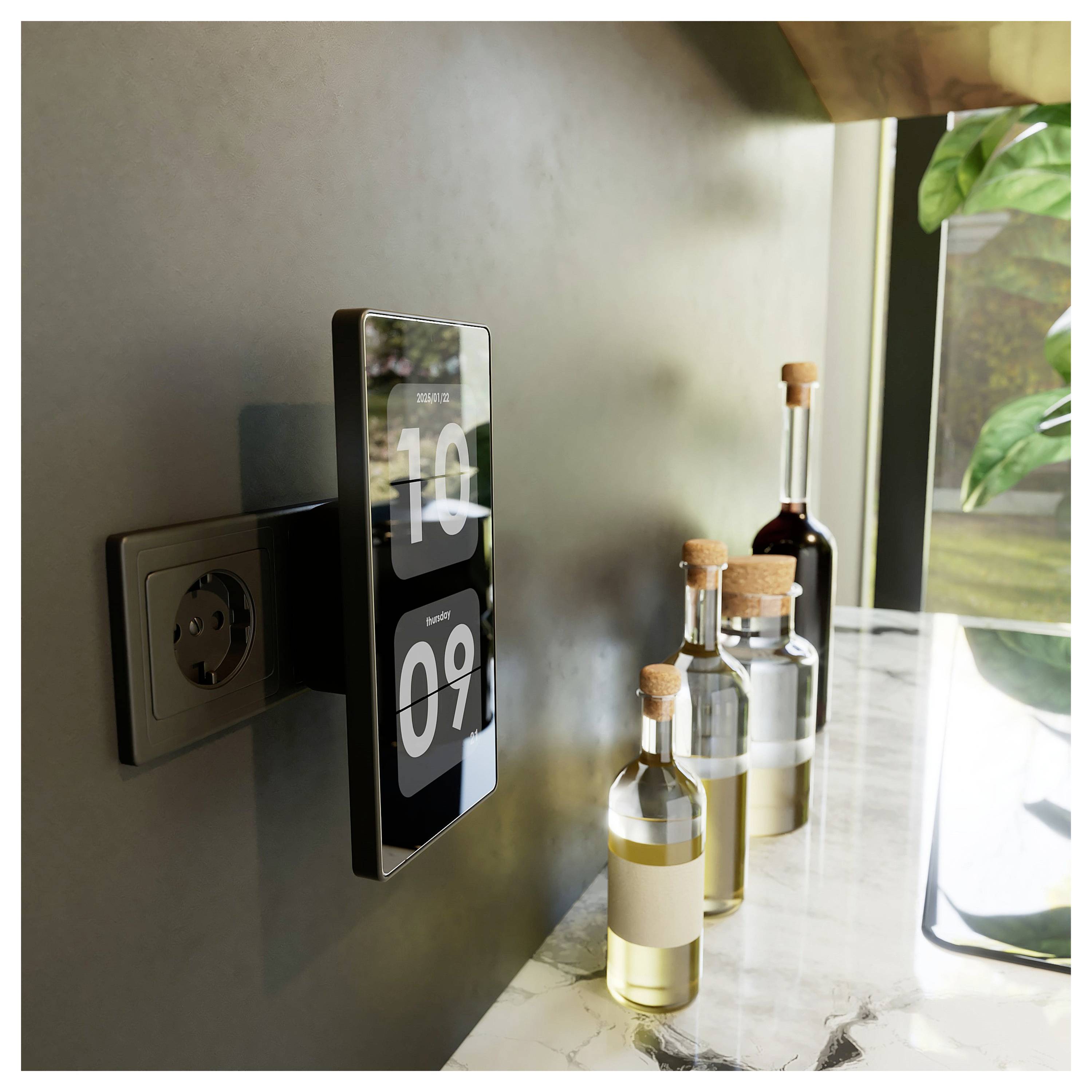Eine an der Wand befestigte digitale Uhr, die '10:09' anzeigt, in der Nähe einer Küchenablage, mit Flaschen Olivenöl und Essig daneben, nahe einem Fenster.