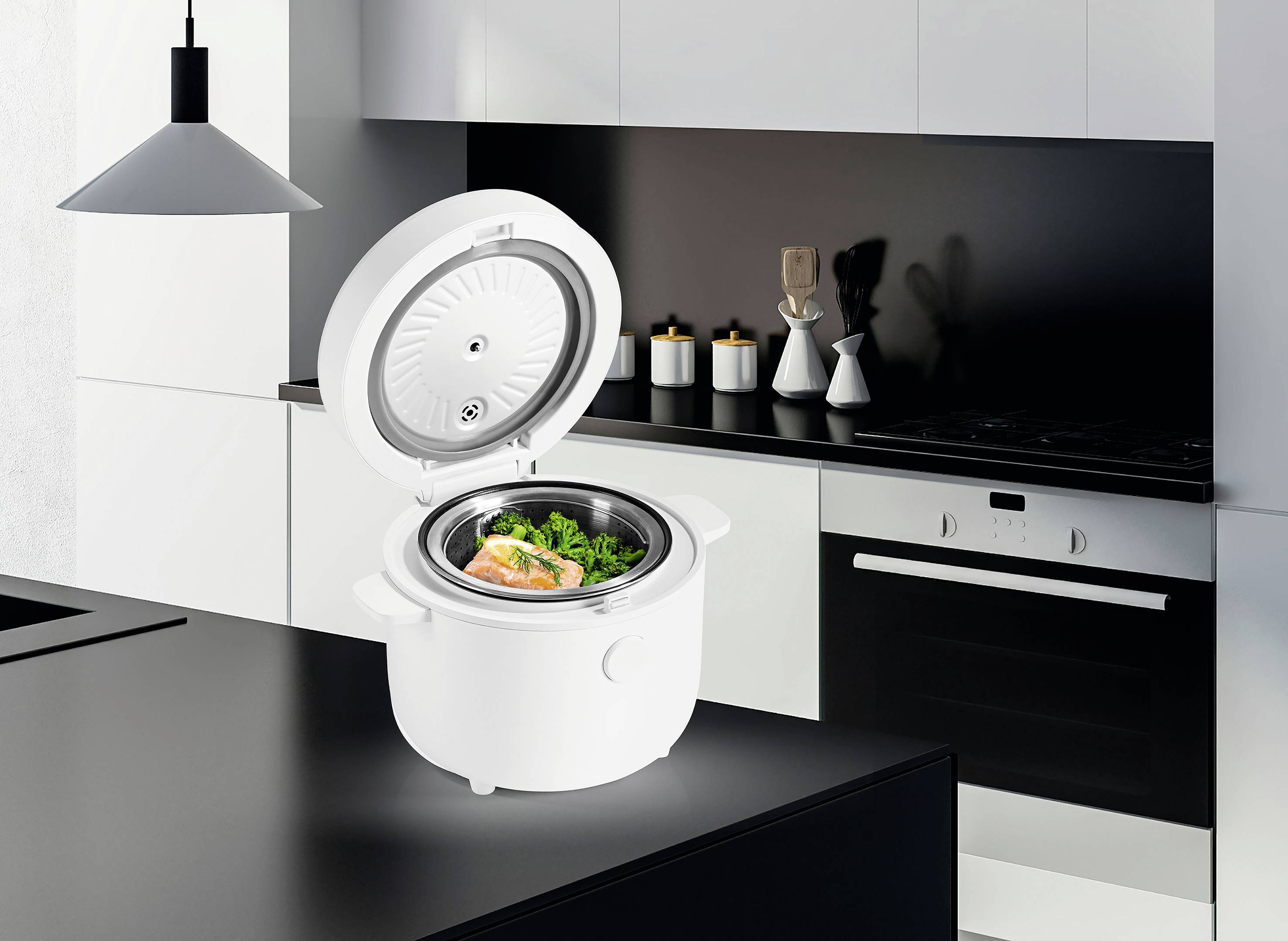 Eine moderne Küche mit weißen Schränken und schwarzen Akzenten, in der auf der Arbeitsplatte ein kleiner, offener Reiskocher mit Lachs und Brokkoli steht.