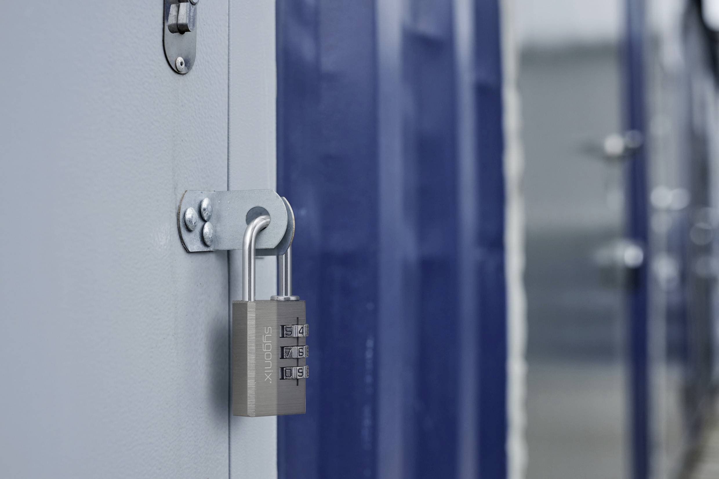 Ein Metallkombinationsschloss sichert eine blaue und graue Metalltür und betont dabei Sicherheit und Schutz.