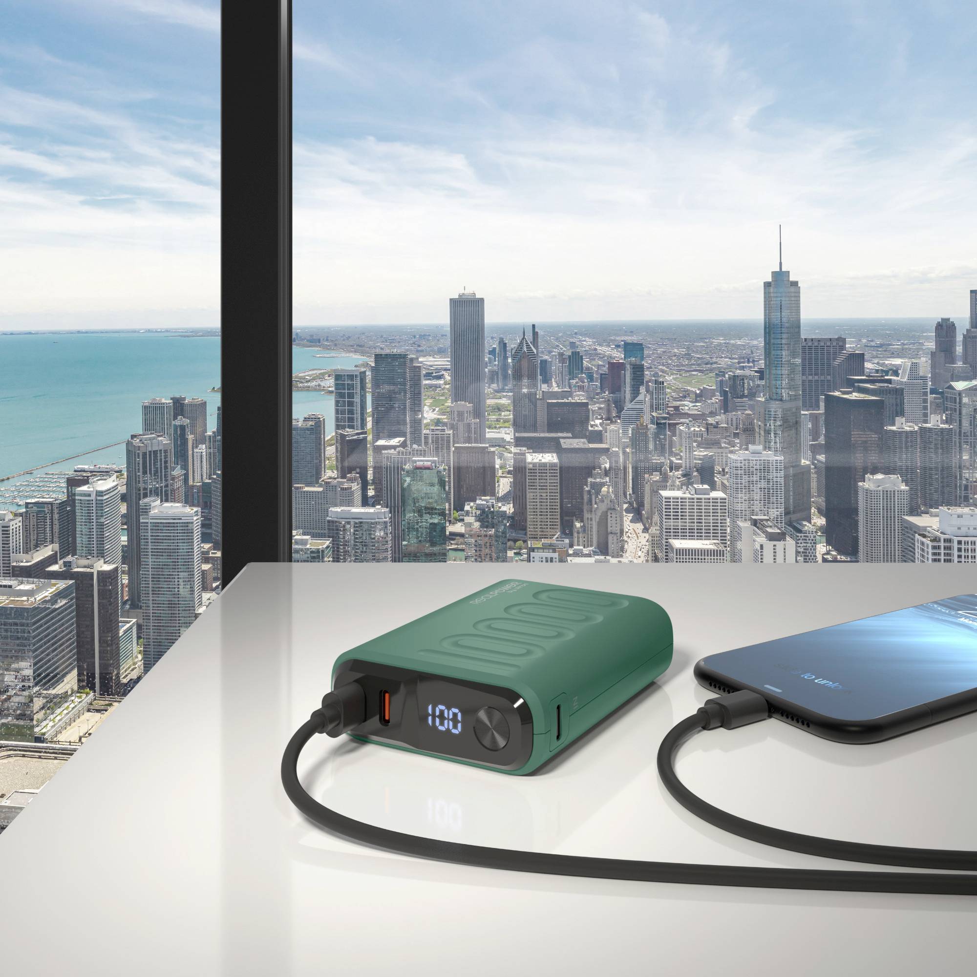 Powerbank lädt ein Smartphone auf einem Tisch mit Blick auf eine Stadtsilhouette durch große Fenster im Hintergrund.