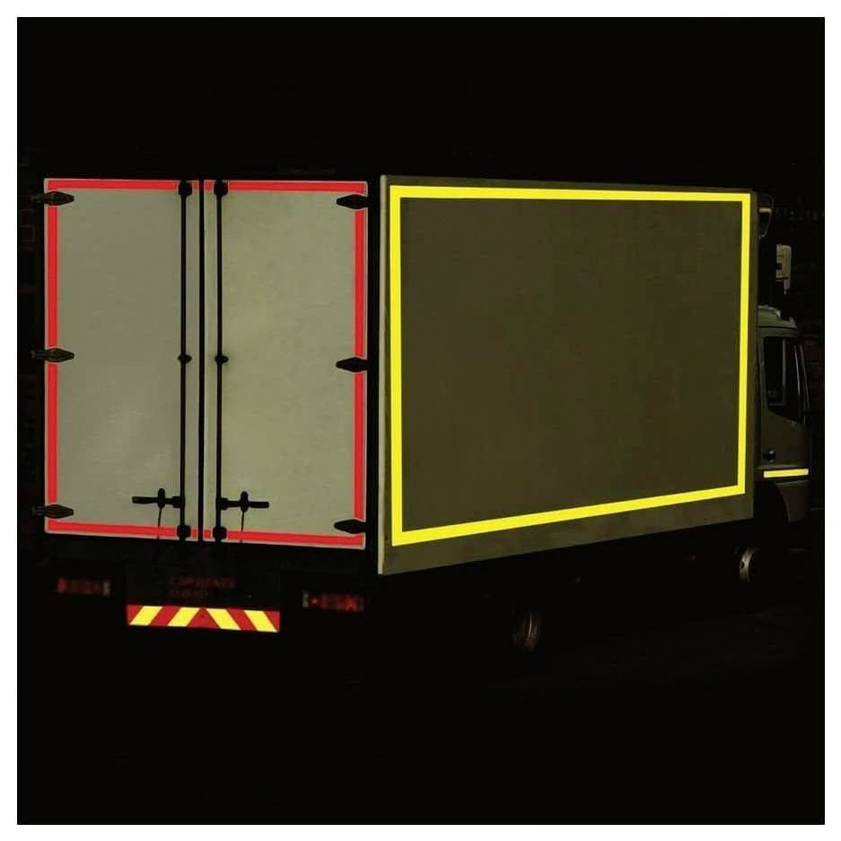 Ein Lastwagen bei Nacht mit reflektierendem roten und gelben Klebeband, das seine Rückseite und Seite umrahmt und die Sichtbarkeit und Sicherheit auf der Straße verbessert.