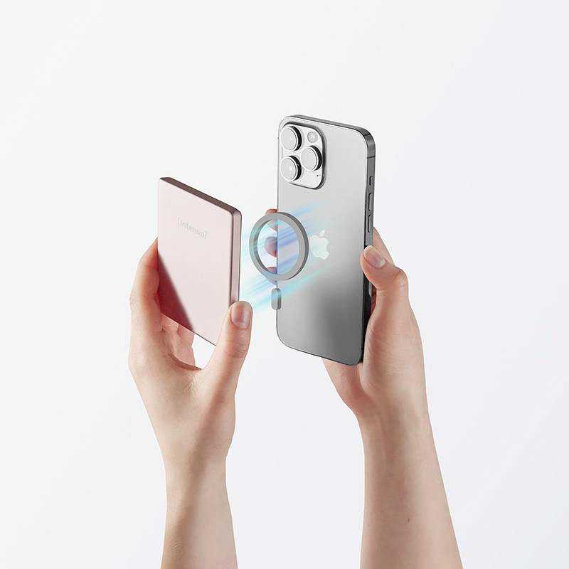 Zwei Hände, die eine rosa magnetische Powerbank an ein silbernes Smartphone mit sichtbarem Apple-Logo und dreifacher Kamera anlegen.