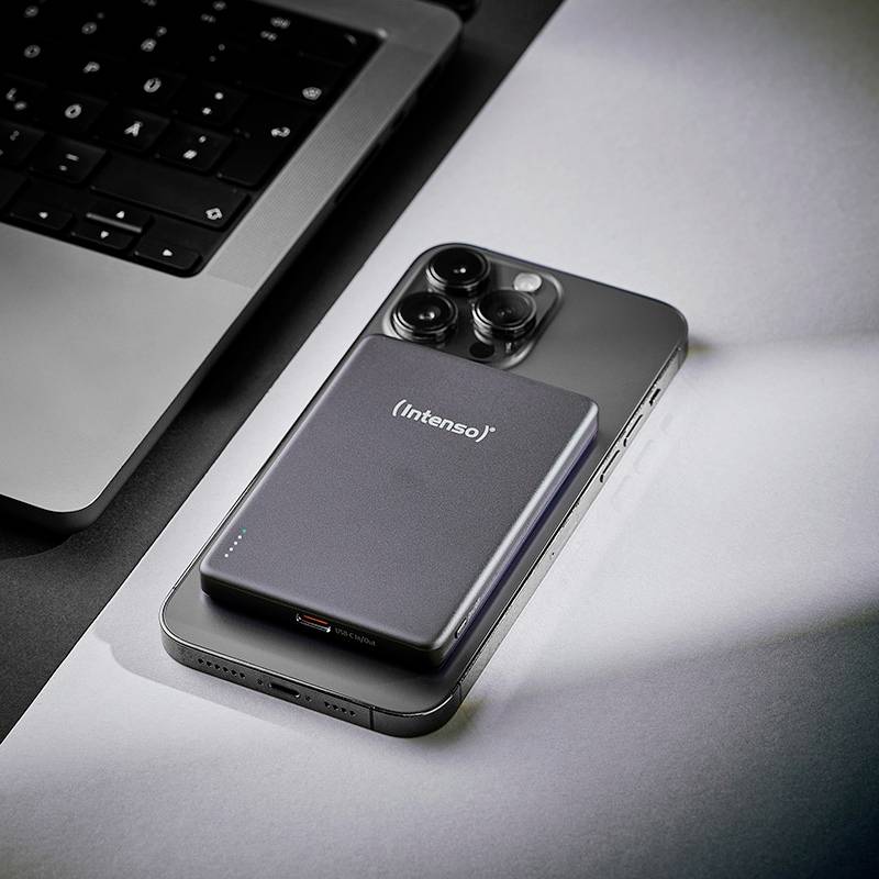 Eine schlanke Powerbank mit 'Intenso'-Branding liegt neben einem Smartphone auf einem Laptop und deutet auf eine technische Einrichtung oder Ladesituation hin.
