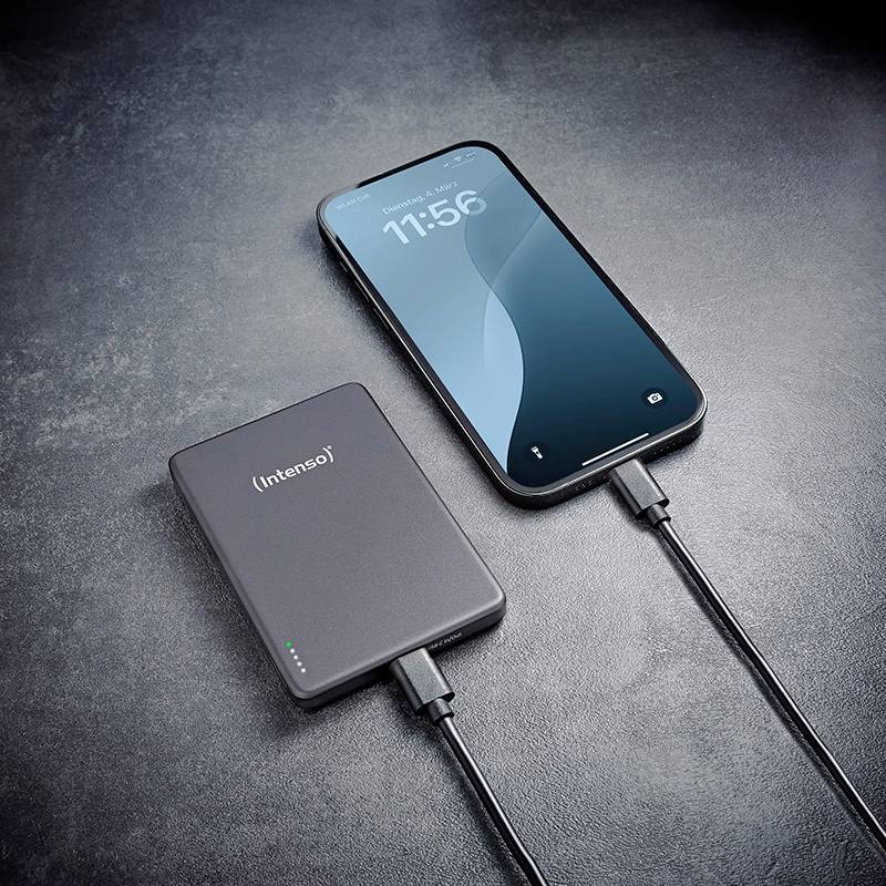 Ein Smartphone, das von einer Intenso Powerbank aufgeladen wird, beide durch Kabel verbunden, auf einer dunklen Oberfläche platziert. Das Handy zeigt 11:56 Uhr.