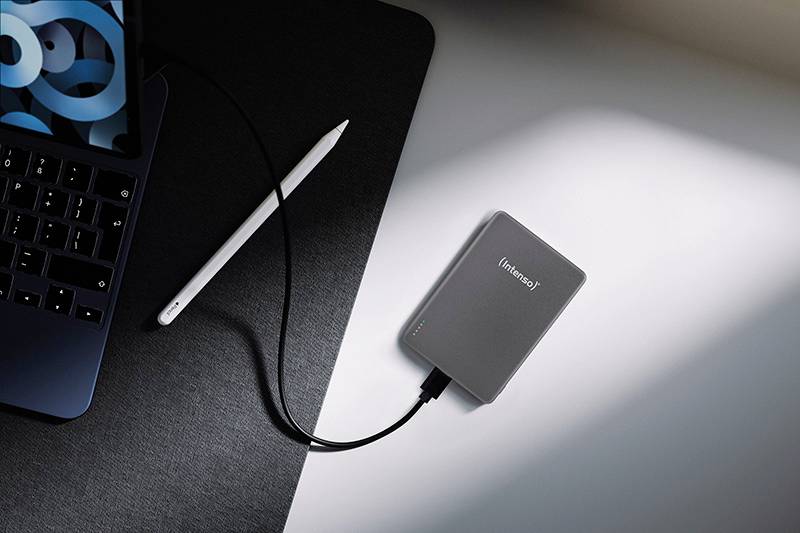 Ein Laptop, der an einer externen Festplatte auf einem Schreibtisch angeschlossen ist, mit einem Stylus in der Nähe, was eine technische Arbeitsplatz-Einrichtung andeutet.