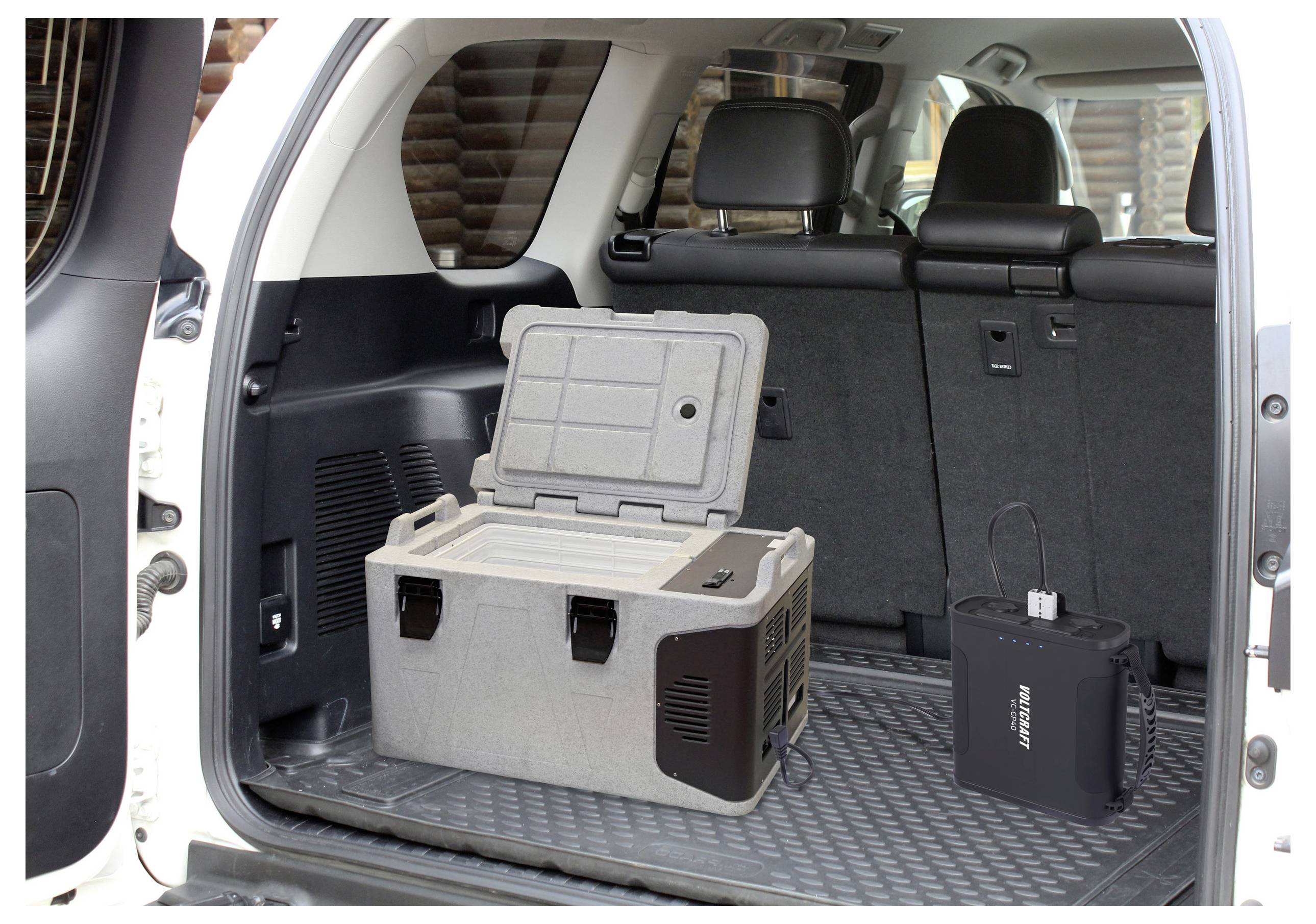 „Kühlbox im Kofferraum des Fahrzeugs mit geöffnetem Deckel neben einer tragbaren Stromstation, die praktische Reisespeicherung und eine Stromlösung veranschaulicht.