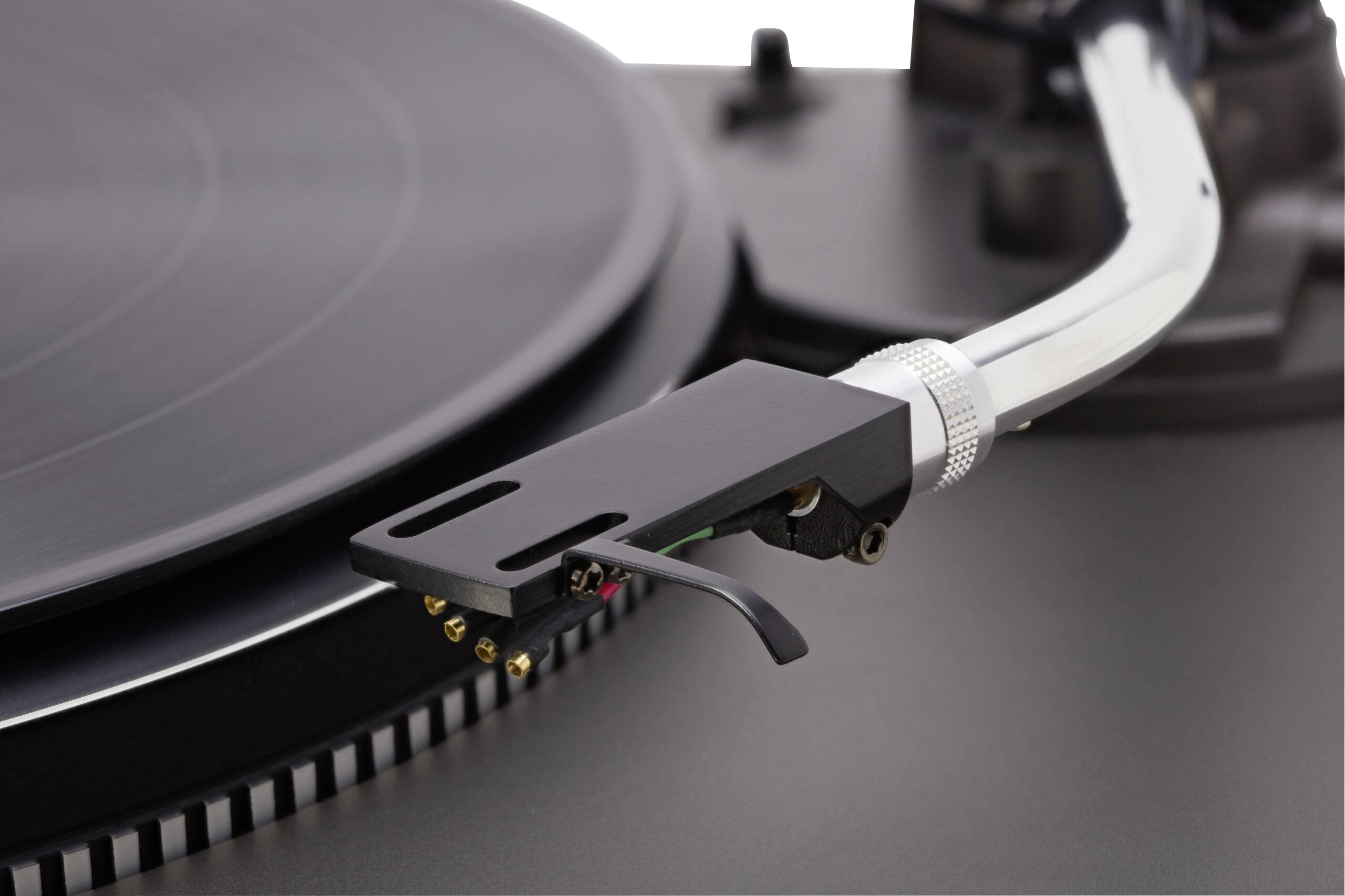 Ein Nahaufnahmefoto eines Plattenspieler-Arms und einer Nadel, die über einer Vinylplatte auf einem Plattenteller positioniert ist.