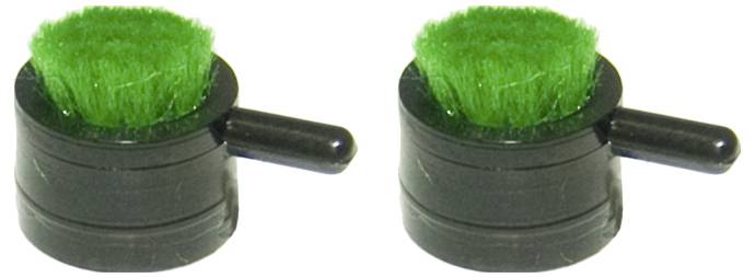 Zwei kleine schwarze Objekte mit grünen Borsten und seitlichen Griffen, die wie Mini-Schrubber aussehen, nebeneinander auf einem weißen Hintergrund.