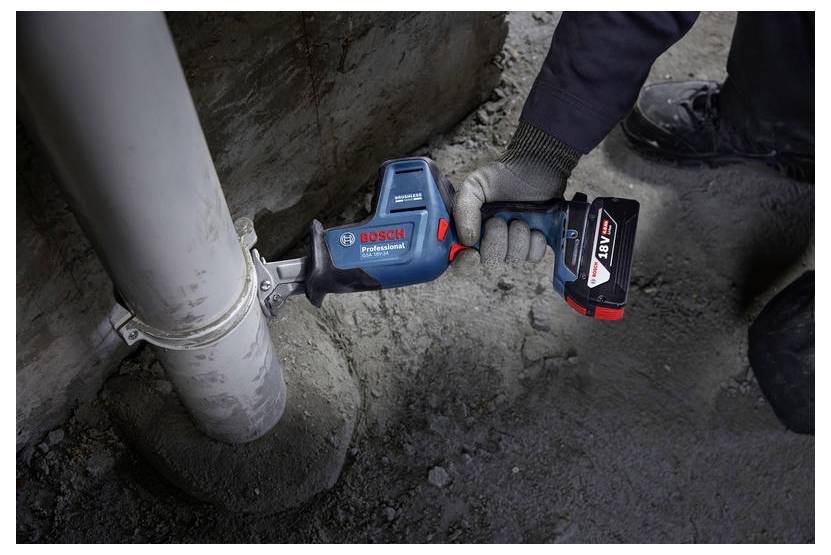 Eine Person verwendet eine blaue und rote Bosch Professional Elektrosäge, um ein Metallrohr in einer Baustellenumgebung zu schneiden.