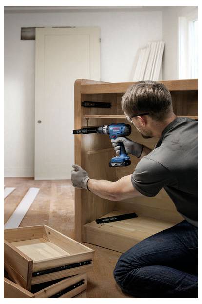 Eine Person montiert Möbel mit einer Elektrobohrmaschine in einem Raum mit Holzfußboden und unterstreicht damit eine Heimwerkeraktivität.