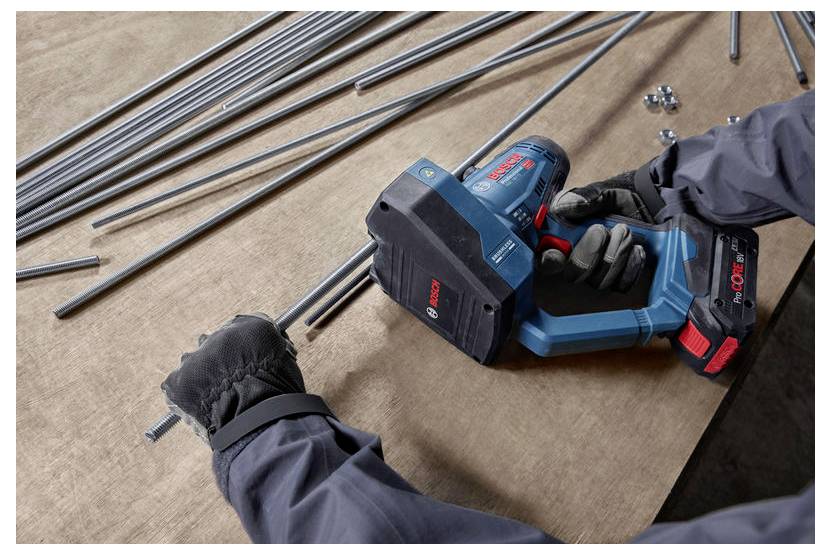 Eine Person mit Schutzhandschuhen verwendet ein blau-rotes Elektrowerkzeug, um mehrere Metallstäbe auf einer Holzoberfläche zu schneiden.