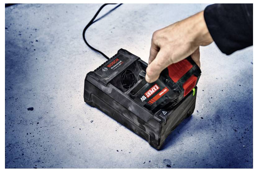 Eine Hand legt einen Bosch-18V-Akku in eine Ladestation auf einer blau-grauen Oberfläche und zeigt damit eine Ladungsvorgang an.