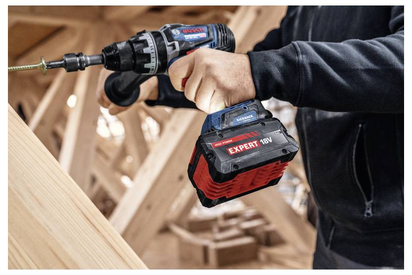 Eine Person verwendet einen Bosch Akku-Bohrer mit einer 18V Expert Batterie, um Schrauben in Holz zu befestigen, höchstwahrscheinlich auf einer Baustelle.
