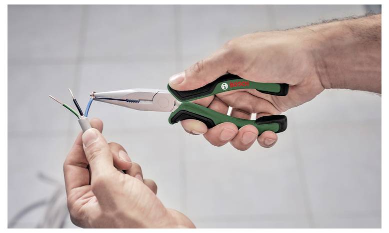 Eine Person benutzt eine Zange, um das Ende eines mehrfarbigen elektrischen Kabels auszustrippen und es für die Installation oder Reparatur vorzubereiten.