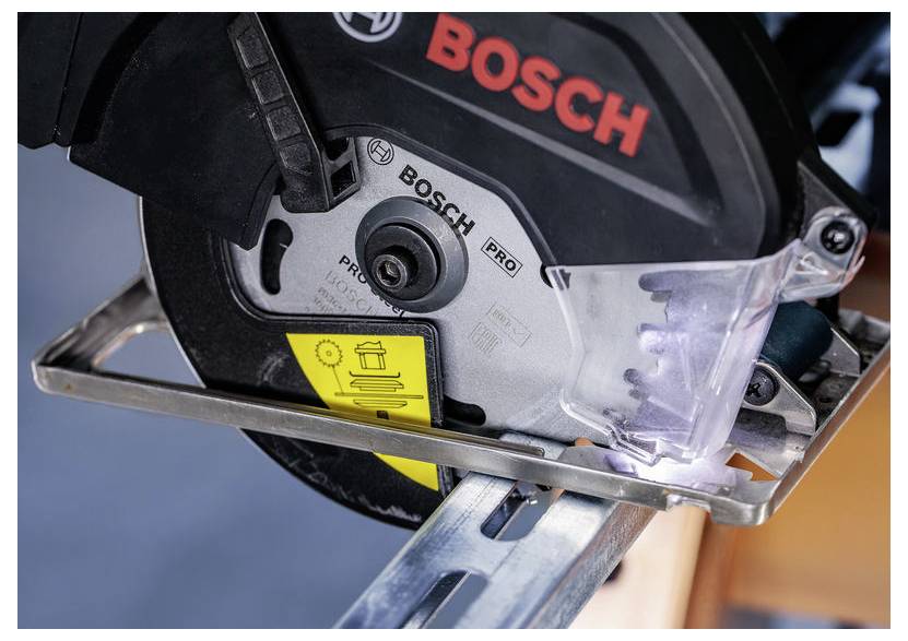 Ein Kreissägeblatt mit dem Bosch-Logo schneidet durch eine Metallführungsschiene, wobei ein Sicherheitswarnaufkleber am Gerät sichtbar ist.