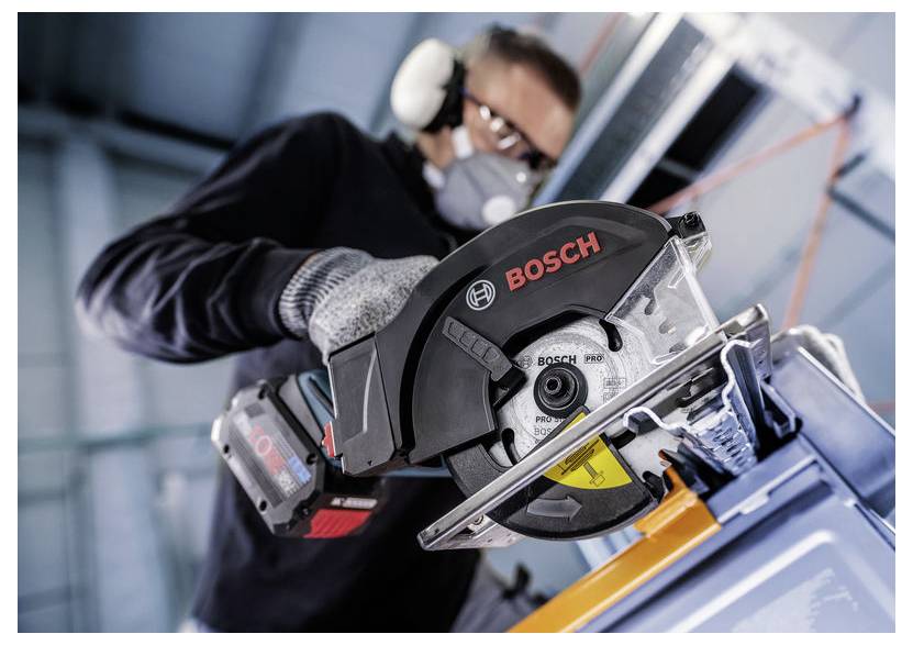 Person mit Sicherheitsausrüstung verwendet eine Bosch-Kreissäge im Innenbereich und konzentriert sich darauf, Material zu durchtrennen.