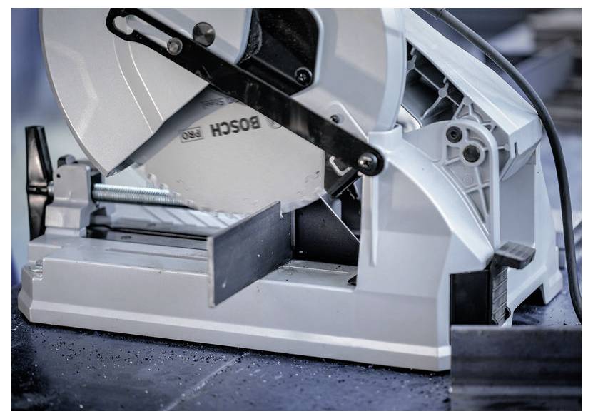 Eine Nahaufnahme einer Kreissäge, die Metall schneidet, wobei die Sägeblatt und das eingeklemmte Werkstück zu sehen sind. Die Säge ist auf einer Werkbank in einer Werkstatt positioniert.