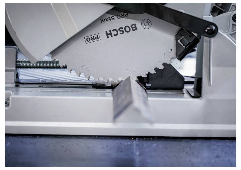 Eine Metallsäge schwebt über einem L-förmigen Metallstück, bereit zum Schneiden. Die Säge trägt die Markenaufschrift 