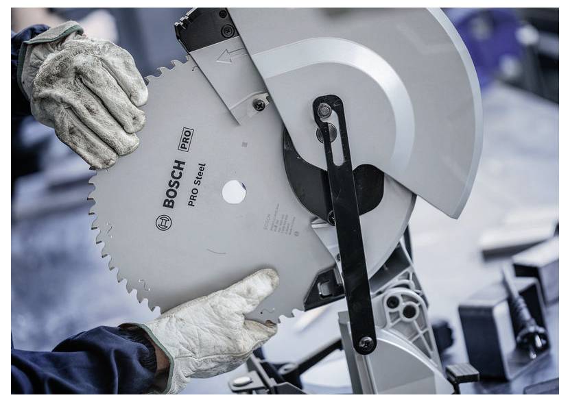 Hände mit Handschuhen, die eine Bosch Pro Steel Kreissägeblatt in eine Kreissäge einsetzen, was Werkzeugnutzung und Sicherheitsausrüstung zeigt.