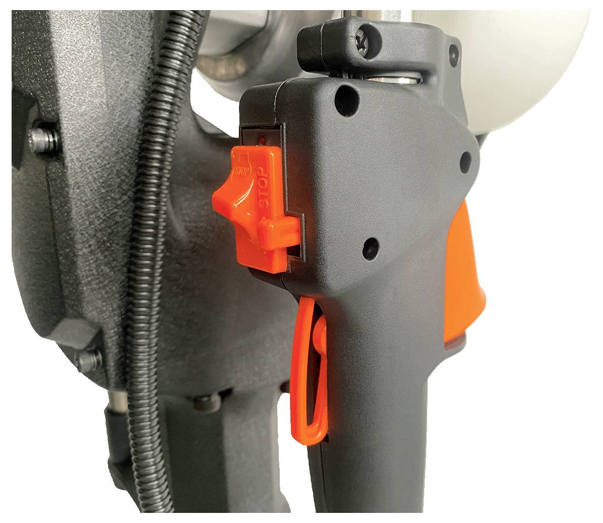 Nahaufnahme eines schwarzen Griffs mit einem orangefarbenen Sicherheitsauslöser und Knopf, der Teil größerer Maschinerie ist und industrielle oder mechanische Verwendung andeutet.