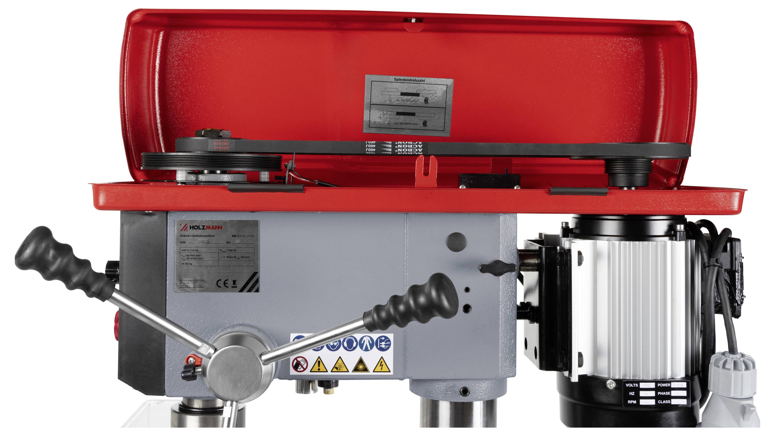 Eine rote und graue Industriemaschine mit Hebeln und einem Motor, die für mechanische Arbeiten verwendet wird und Warnaufkleber an ihrem Gehäuse trägt.